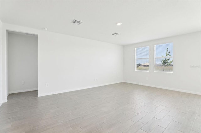 empty room featuring baseboards, light wood finished floors, visible vents, and recessed lighting