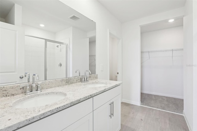 full bath with wood finished floors, visible vents, a sink, and a stall shower
