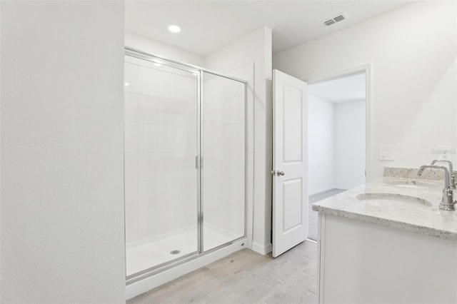 bathroom with recessed lighting, a shower stall, wood finished floors, visible vents, and a sink