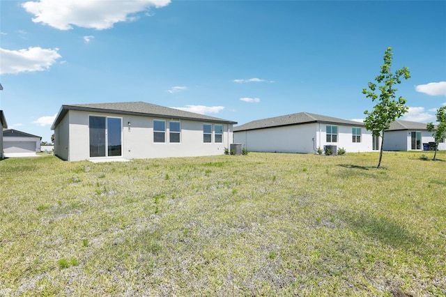back of property with a yard and stucco siding