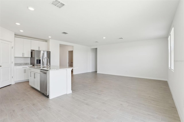 kitchen with white cabinets, recessed lighting, an island with sink, appliances with stainless steel finishes, and open floor plan