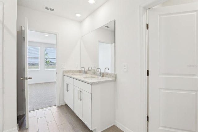 bathroom with recessed lighting, double vanity, visible vents, and a sink