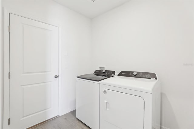 laundry area with baseboards, light wood-type flooring, separate washer and dryer, and laundry area