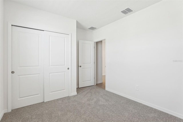 unfurnished bedroom with baseboards, carpet floors, visible vents, and a closet