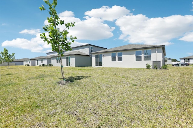 back of property with a lawn and stucco siding