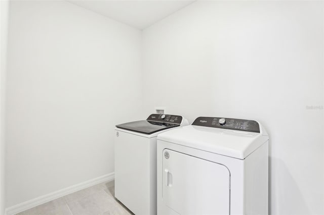 clothes washing area featuring light tile patterned floors, washing machine and clothes dryer, baseboards, and laundry area