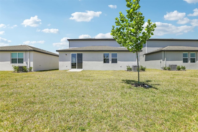 rear view of house with central air condition unit and a lawn
