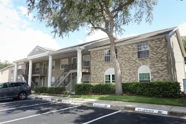 view of property with uncovered parking and stairway