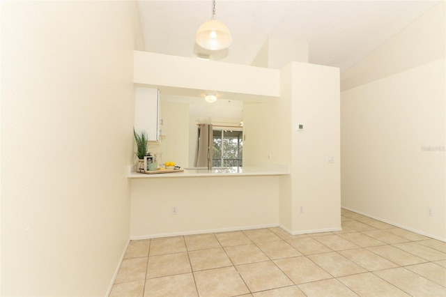 empty room with lofted ceiling, light tile patterned floors, and baseboards