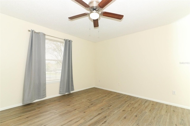 spare room featuring light wood-type flooring, ceiling fan, and baseboards