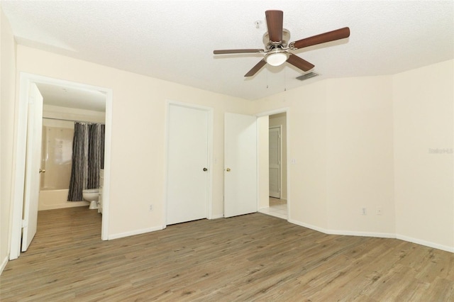 interior space featuring visible vents, light wood-style flooring, ensuite bath, and a textured ceiling