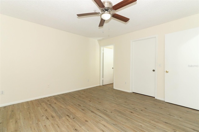 unfurnished bedroom with light wood finished floors, a ceiling fan, and baseboards