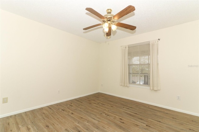 empty room featuring light wood finished floors, ceiling fan, baseboards, and a textured ceiling