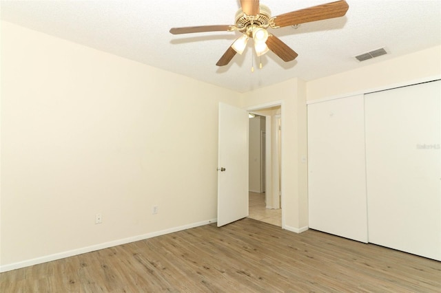 unfurnished bedroom featuring light wood finished floors, baseboards, and a textured ceiling