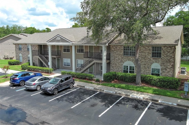 view of building exterior with stairs and uncovered parking