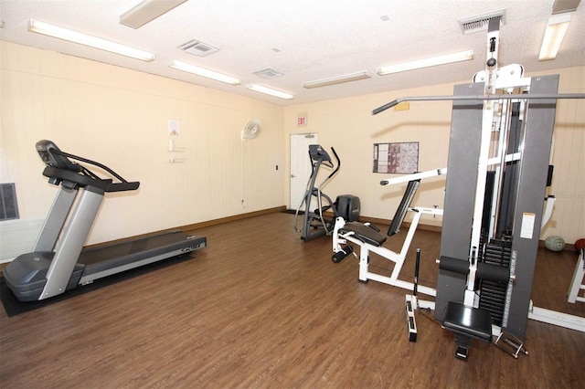 exercise room featuring visible vents, a textured ceiling, and wood finished floors