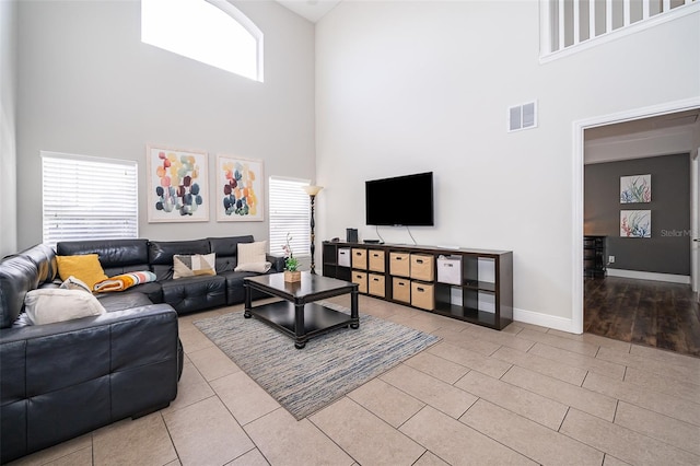 living room featuring baseboards, visible vents, and a towering ceiling