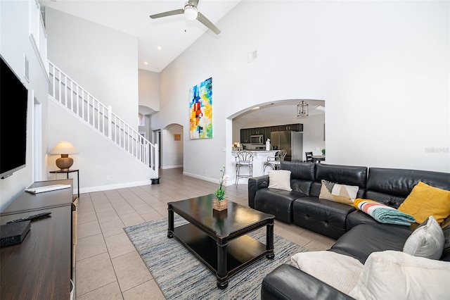 living area with ceiling fan, baseboards, stairway, light tile patterned flooring, and arched walkways