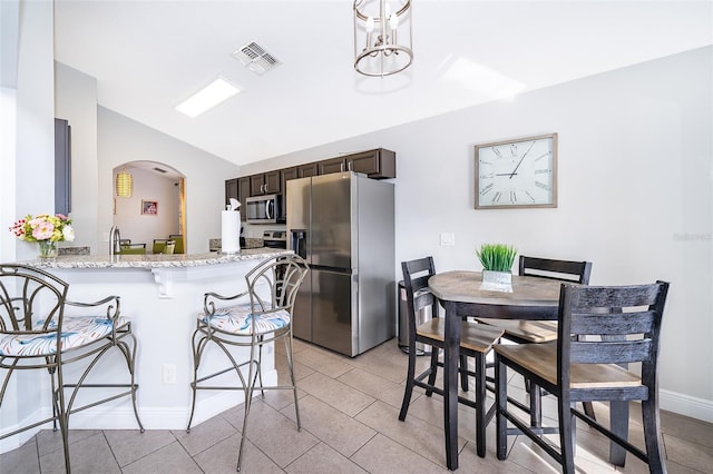 kitchen with light tile patterned floors, visible vents, a breakfast bar, stainless steel appliances, and dark brown cabinetry