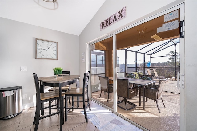 dining area with tile patterned flooring, baseboards, vaulted ceiling, and a sunroom