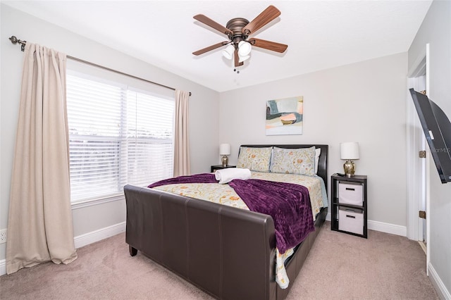 bedroom featuring baseboards, light colored carpet, and a ceiling fan