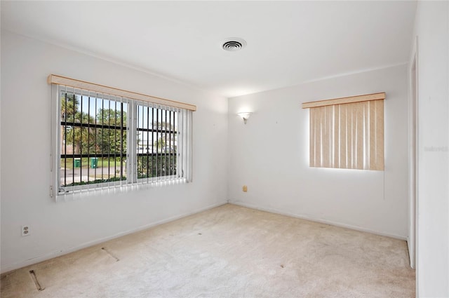 empty room featuring carpet, visible vents, and baseboards