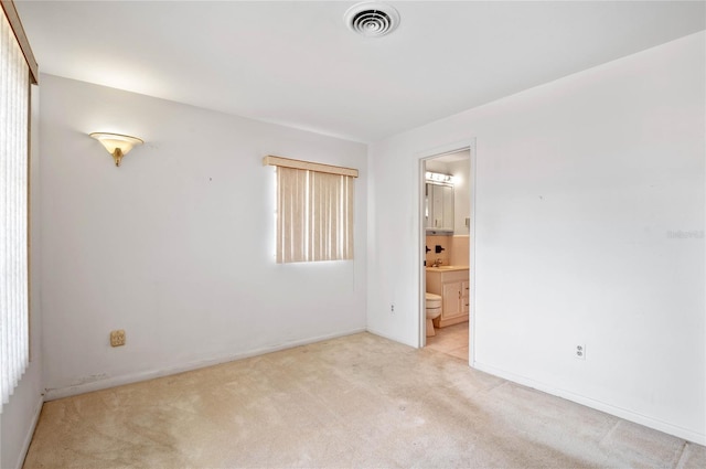 spare room with baseboards, visible vents, and light carpet