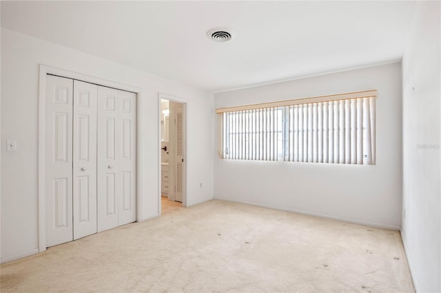 unfurnished bedroom with a closet, carpet flooring, and visible vents