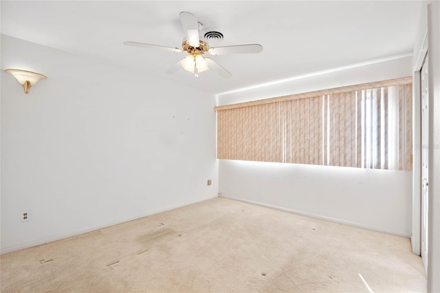 carpeted empty room with visible vents and a ceiling fan