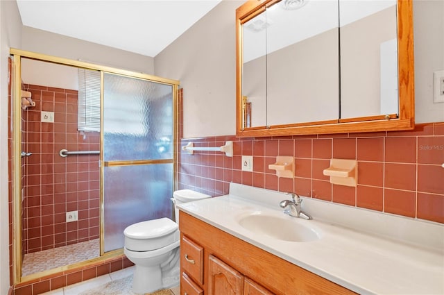 bathroom featuring toilet, a stall shower, tile walls, wainscoting, and vanity