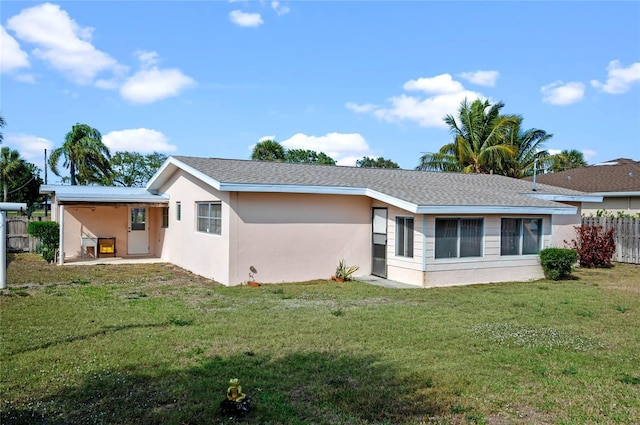 back of property featuring a yard, fence, roof with shingles, and stucco siding