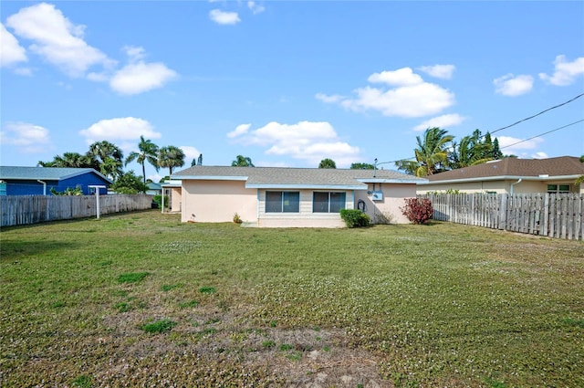 rear view of house with a yard, a fenced backyard, and stucco siding