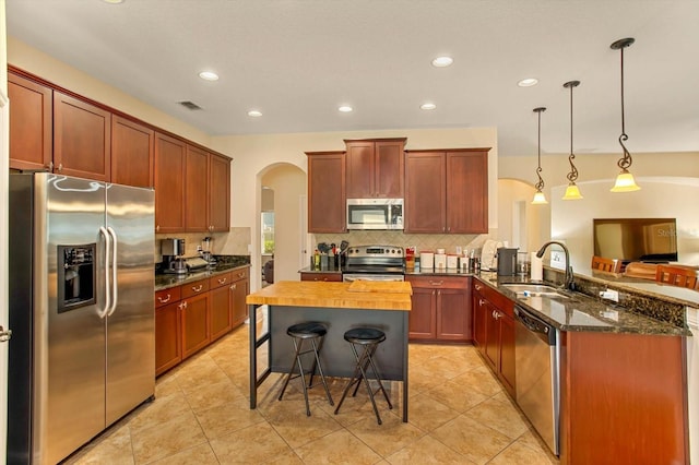 kitchen with arched walkways, visible vents, appliances with stainless steel finishes, a sink, and a peninsula