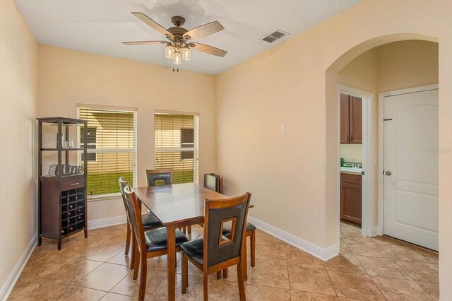 dining room featuring arched walkways, visible vents, baseboards, and light tile patterned floors