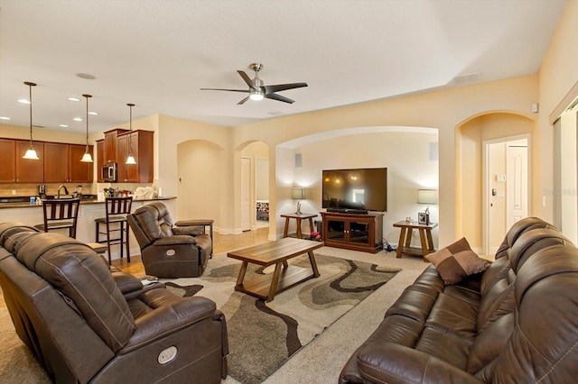 living room with arched walkways, recessed lighting, light colored carpet, ceiling fan, and baseboards