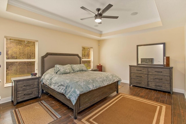 bedroom featuring baseboards, a tray ceiling, dark wood finished floors, and a ceiling fan