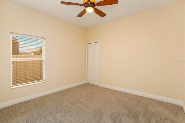 carpeted empty room featuring ceiling fan and baseboards