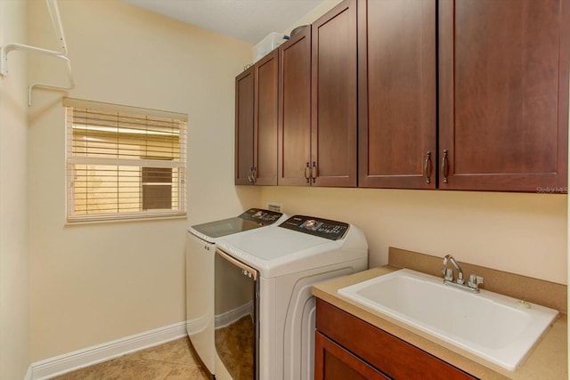 laundry area featuring cabinet space, light tile patterned floors, baseboards, washing machine and clothes dryer, and a sink