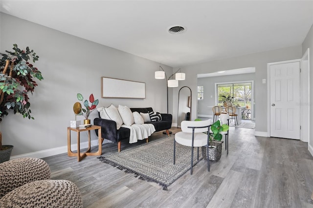 living area featuring visible vents, baseboards, and wood finished floors