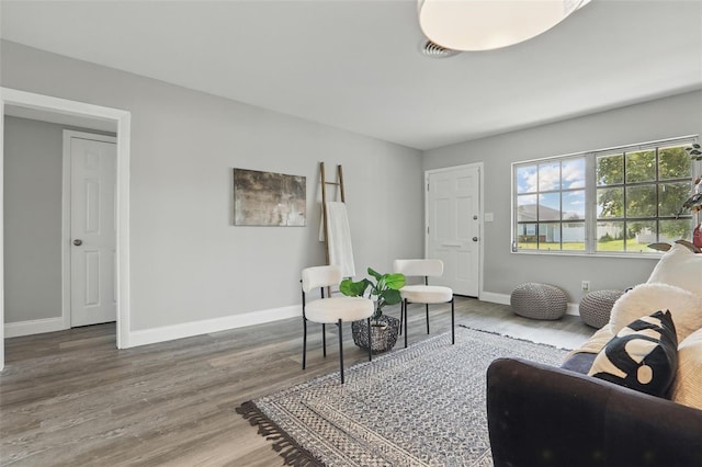 living area with visible vents, wood finished floors, and baseboards