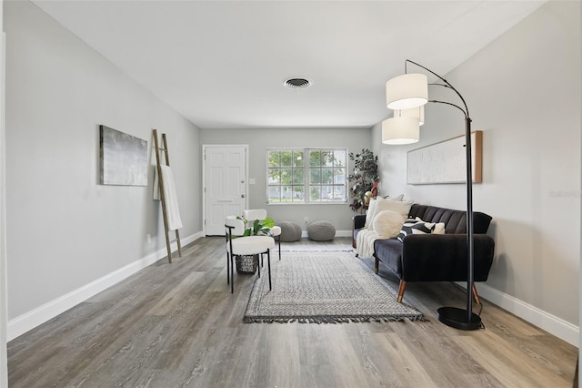 living area with wood finished floors, visible vents, and baseboards