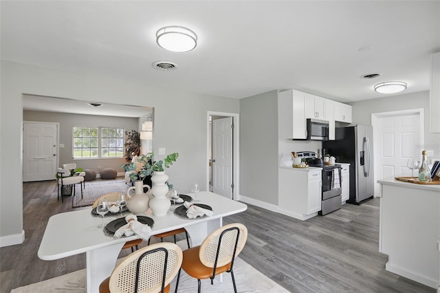 dining space featuring visible vents, baseboards, and wood finished floors