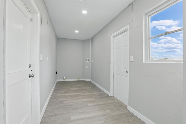 hall featuring light wood finished floors, recessed lighting, baseboards, and a wealth of natural light