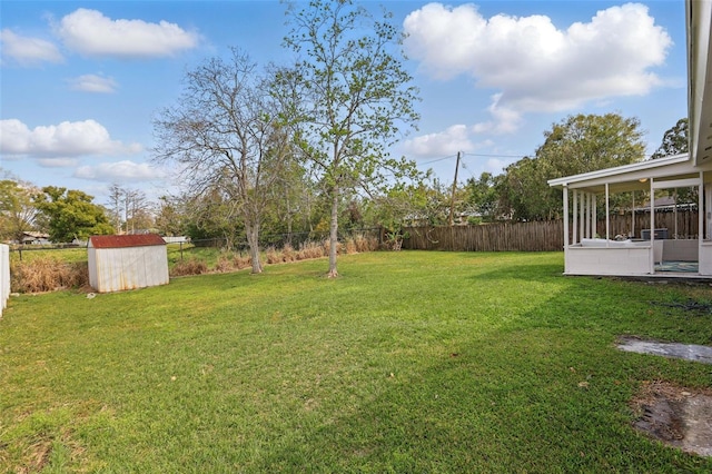 view of yard with a sunroom, an outdoor structure, a fenced backyard, and a shed