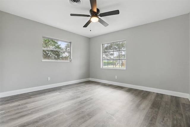 empty room with visible vents, baseboards, a healthy amount of sunlight, and wood finished floors