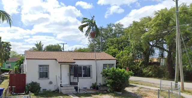 bungalow with fence and stucco siding