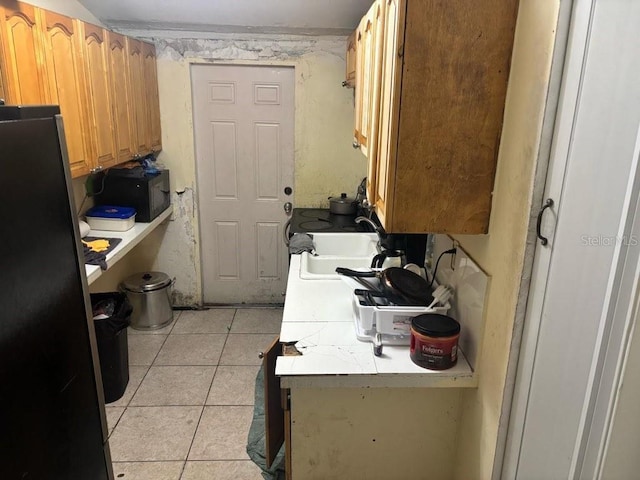 kitchen featuring light tile patterned floors, light countertops, a sink, and freestanding refrigerator