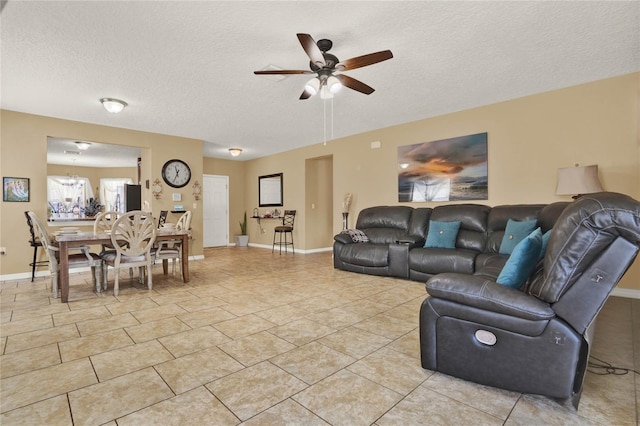 living area with a textured ceiling, light tile patterned floors, ceiling fan with notable chandelier, and baseboards