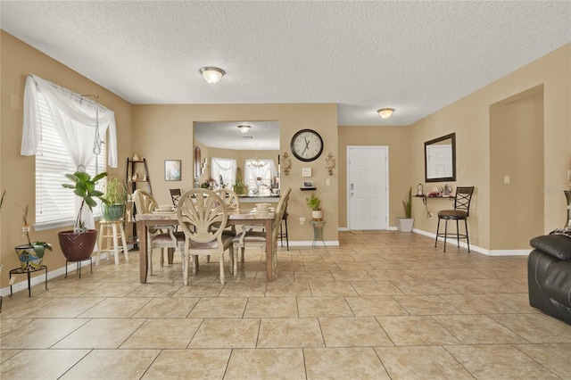 dining area with light tile patterned floors, baseboards, and a textured ceiling