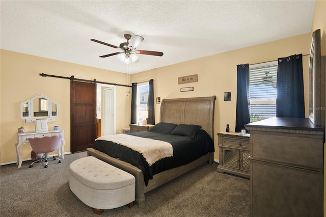 bedroom with a barn door, baseboards, ceiling fan, dark colored carpet, and a textured ceiling